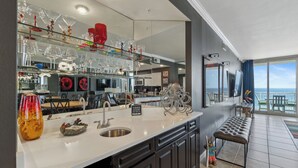 A modern kitchen with a large island, a view of the ocean, and a dining area with a bench.