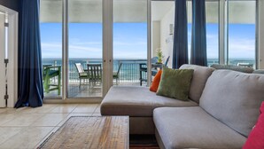 A balcony with a view of the ocean, a sofa with cushions, and a small table.