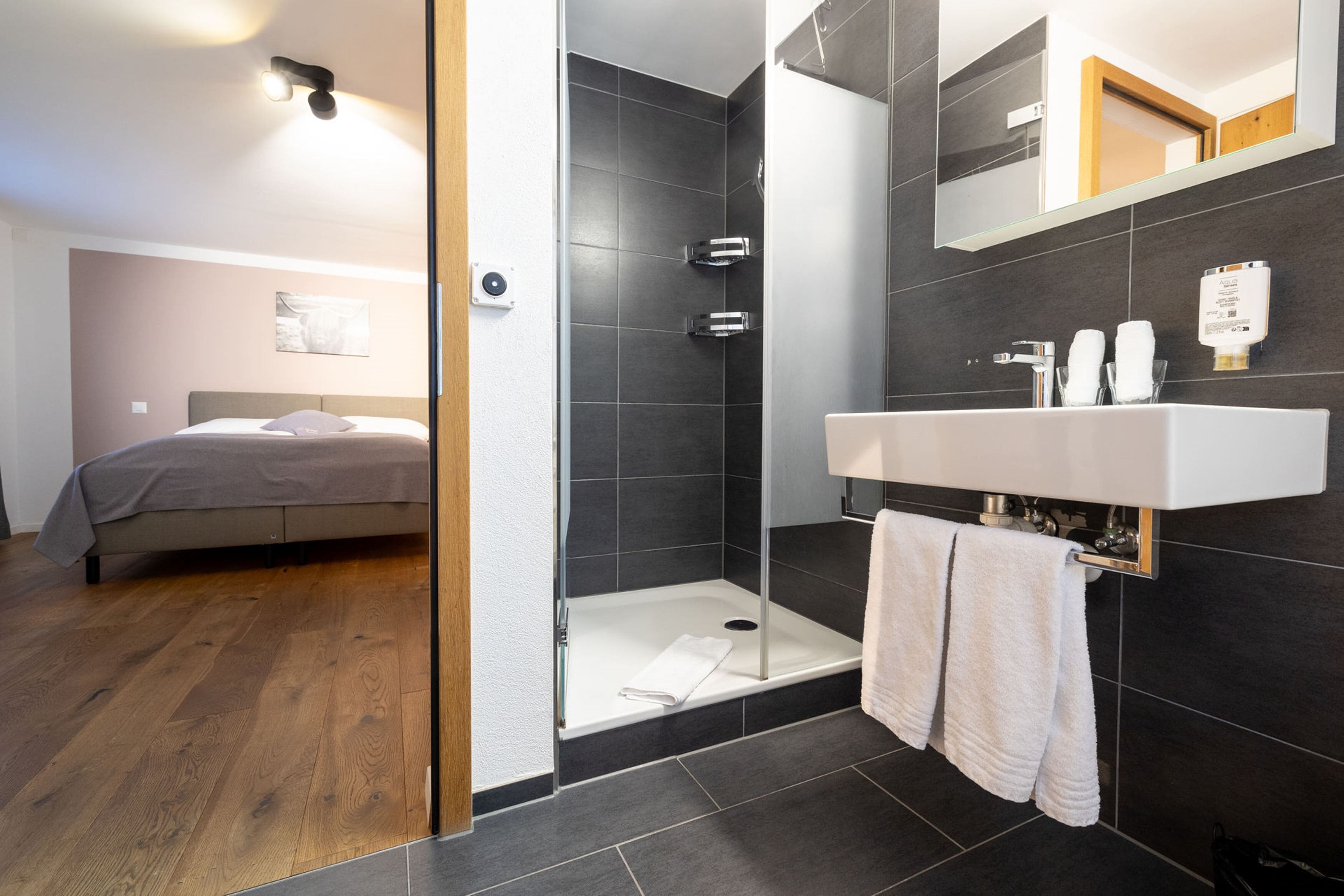 Un baño moderno con ducha, lavamanos y espejo.