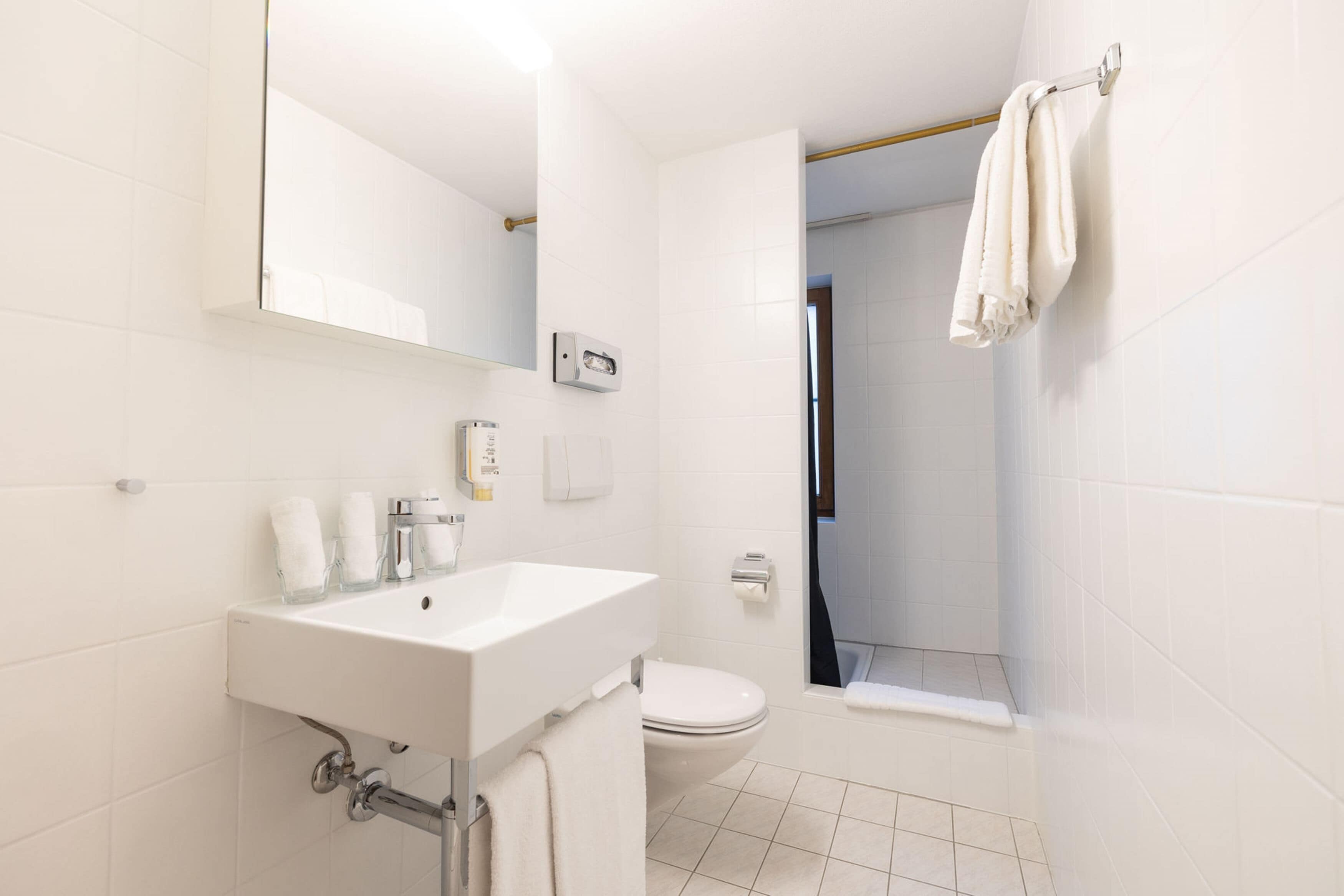 A modern bathroom with a white sink, mirror, and toilet.