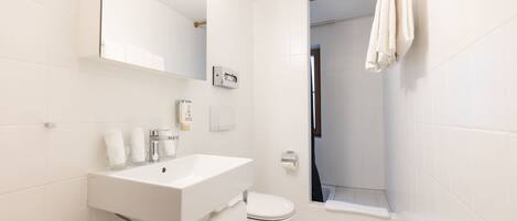 A modern bathroom with a white sink, mirror, and toilet.
