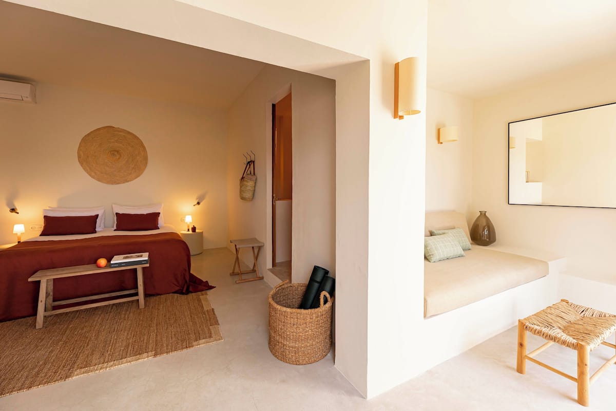 Une chambre à coucher avec un lit, une table de chevet, une lampe et un panier en osier.