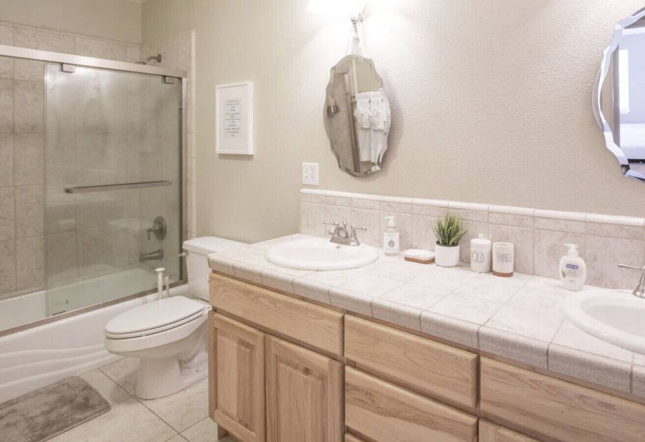 Un baño moderno con ducha envuelta en vidrio, inodoro y tocador con lavabo y espejo.