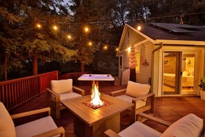 An outdoor deck with a fire pit, wooden furniture, and string lights. - Hot Tub, Privacy, Oversized Deck, Open Floor Plan, Centrally Located! (Mariposa)