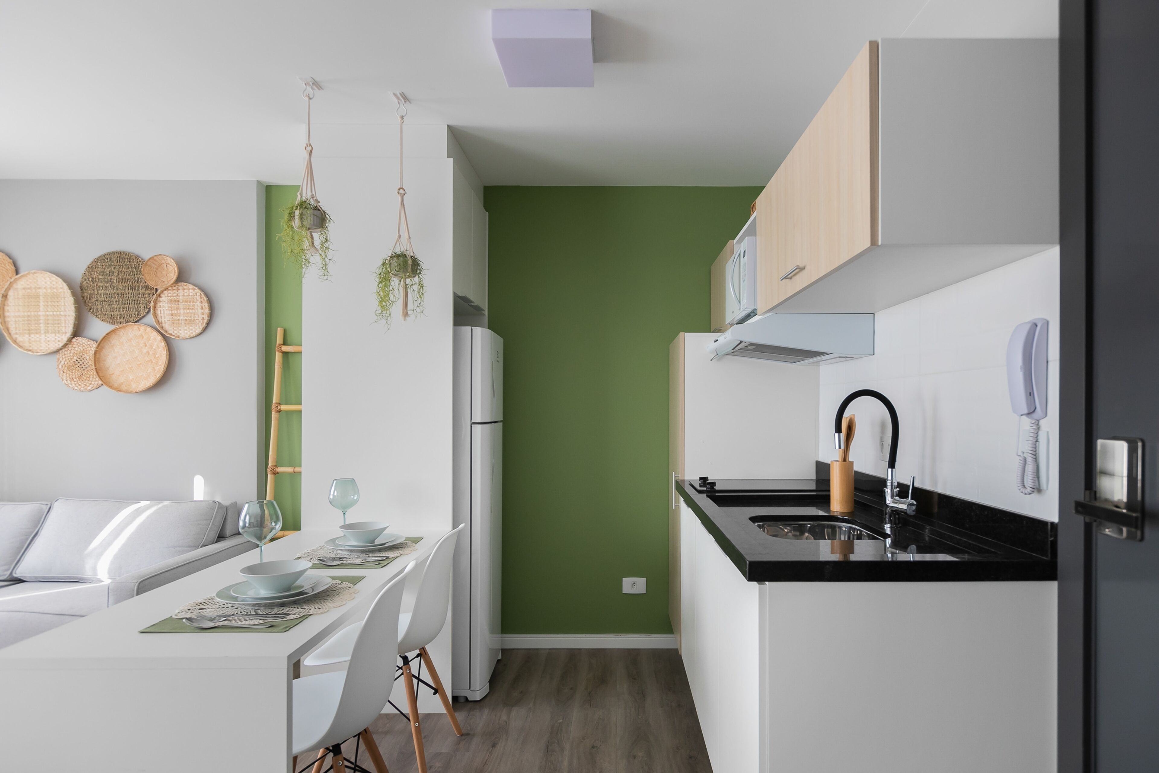 Een moderne keuken met witte kasten, een zwart aanrecht en een groene accentmuur.