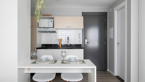 A modern kitchen with white cabinets, a black countertop, and a dining area with a white table and chairs.