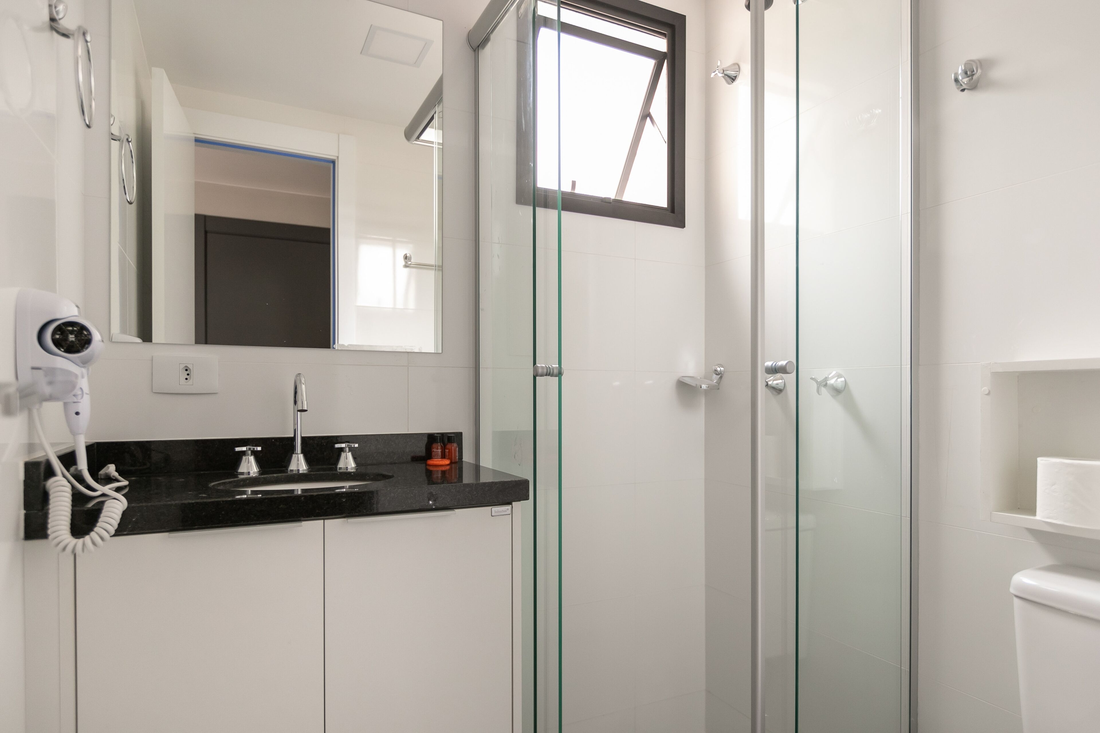 Ein modernes Badezimmer mit einer Duschkabine, einem schwarzen Waschtisch und einer weißen Toilette.