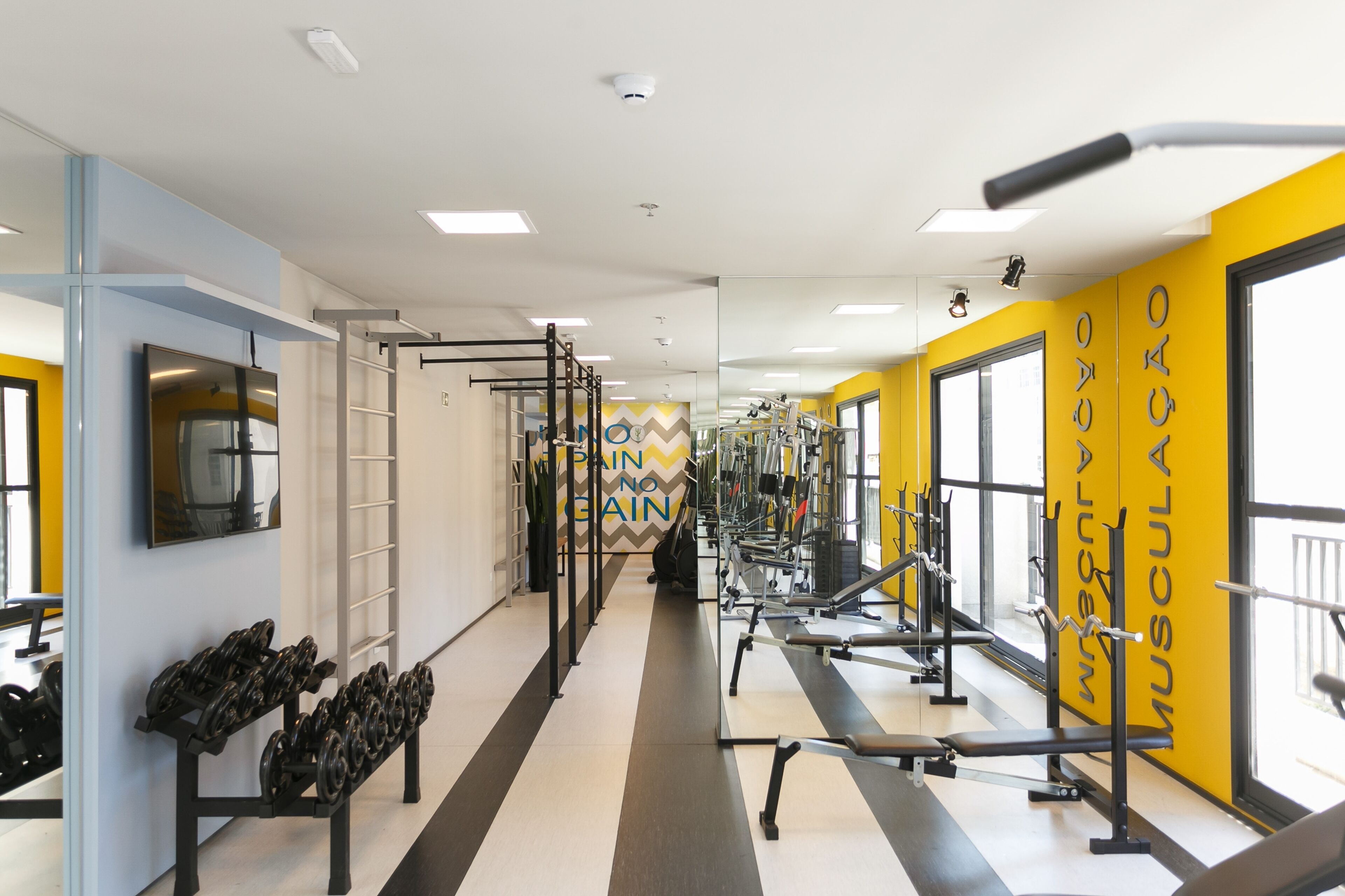 Un gimnasio con equipo de levantamiento de pesas, un espejo y decoración de pared motivacional.