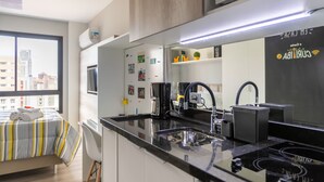 A modern kitchen with a large mirror, black countertops, and a coffee machine.