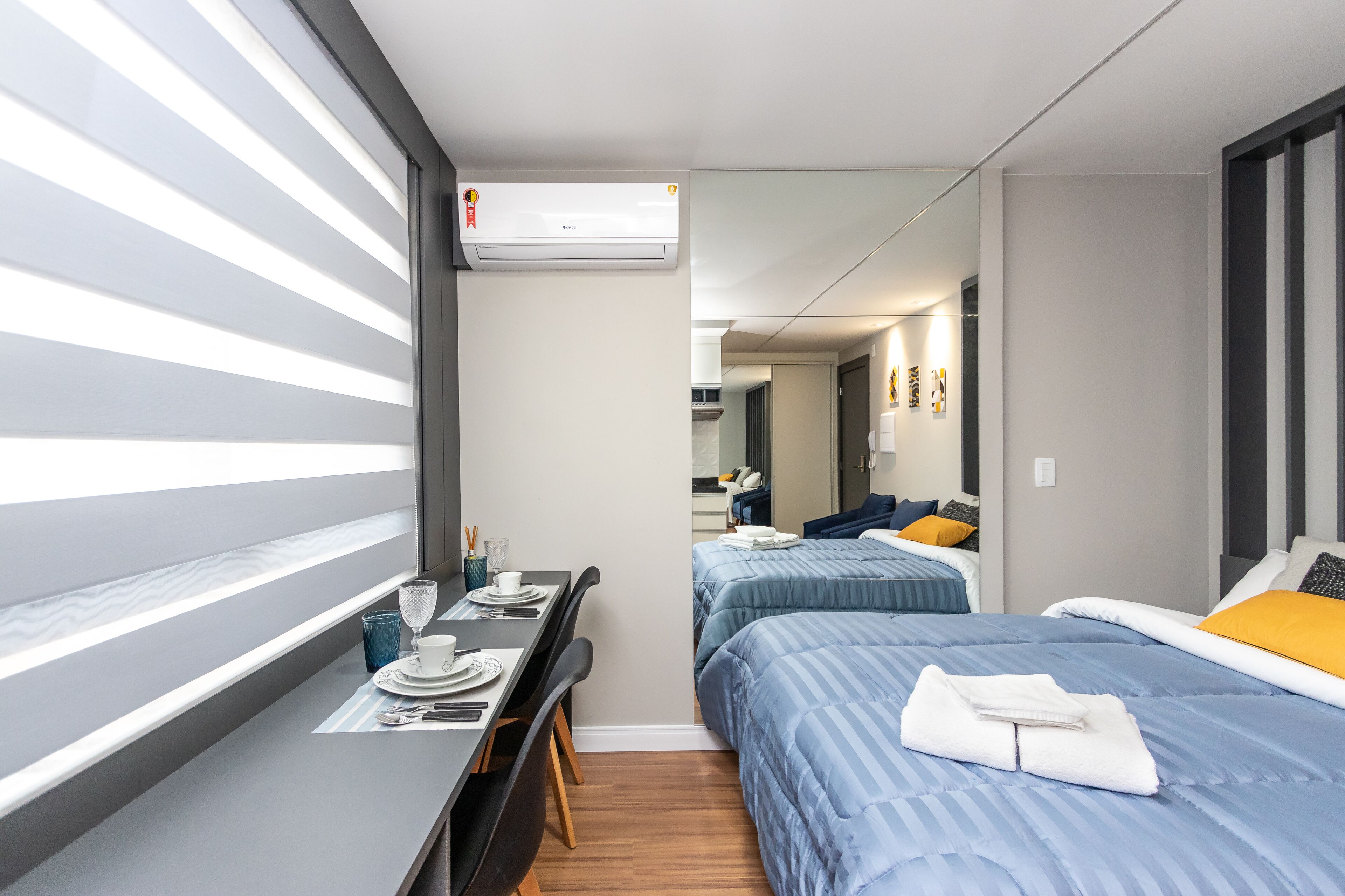 A compact hotel room with a single bed, a small desk with a chair, and a window with blinds.