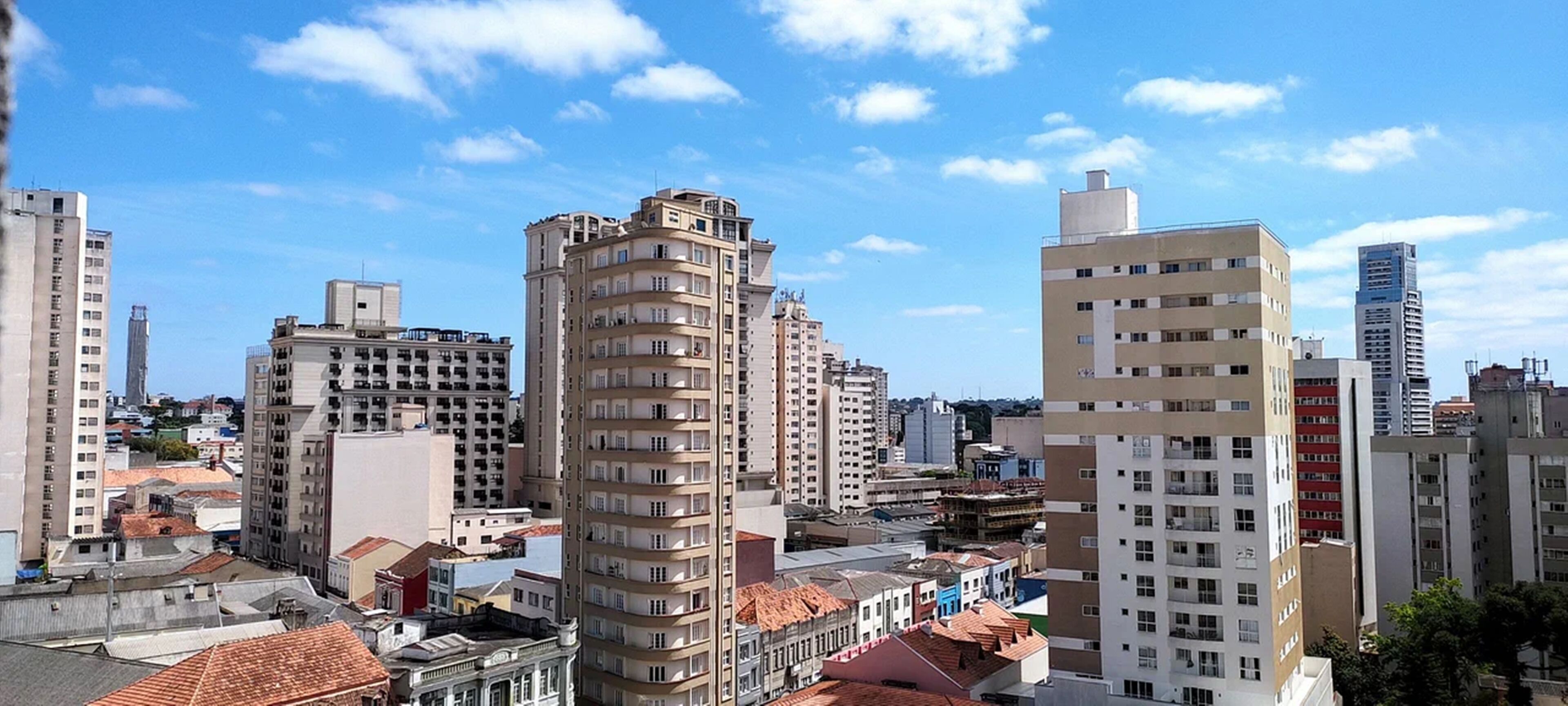 Un paisaje urbano con varios edificios altos, incluyendo un edificio destacado con un diseño arquitectónico único y otros varios con balcones.