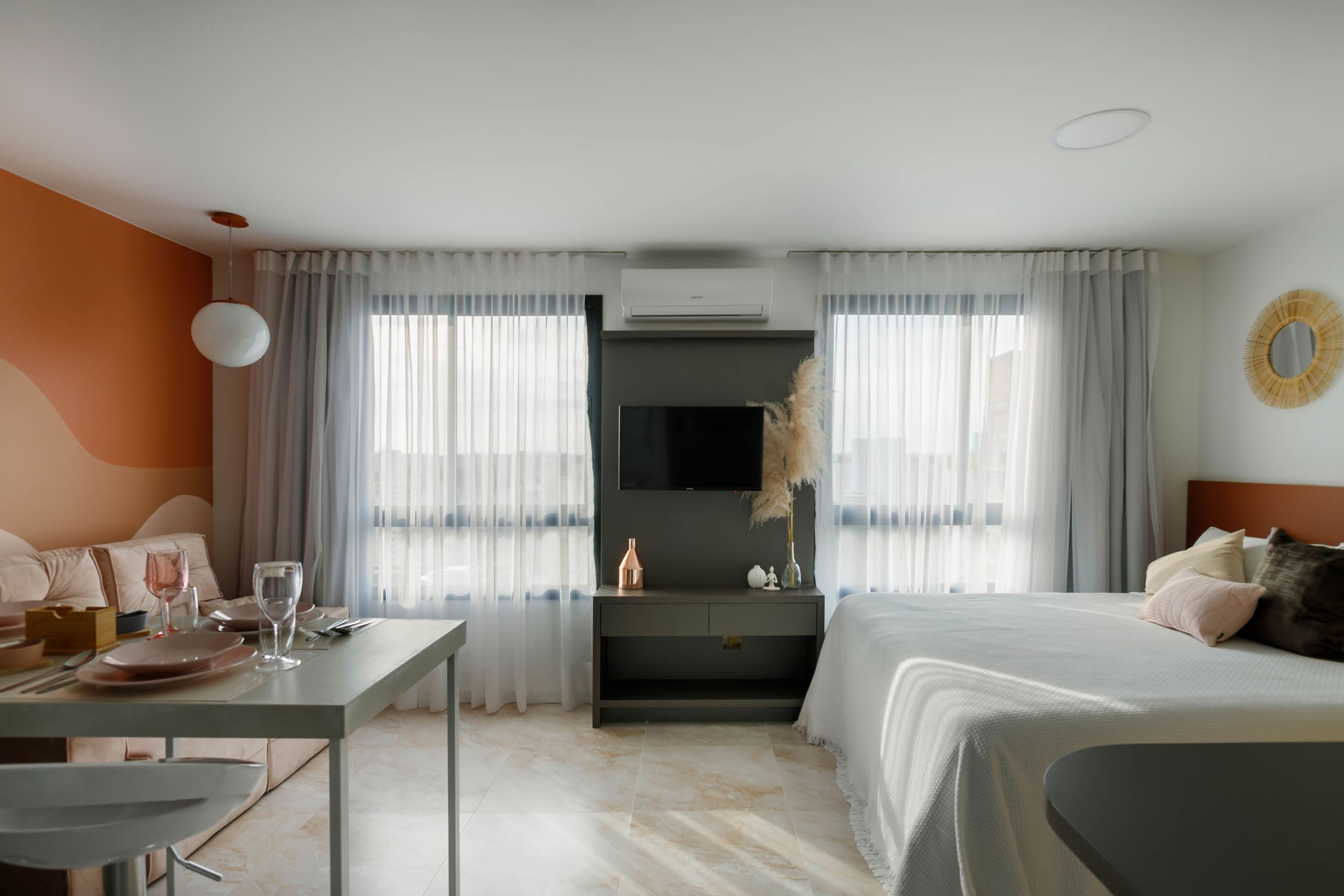 A modern hotel room with a bed, a desk, and a TV.