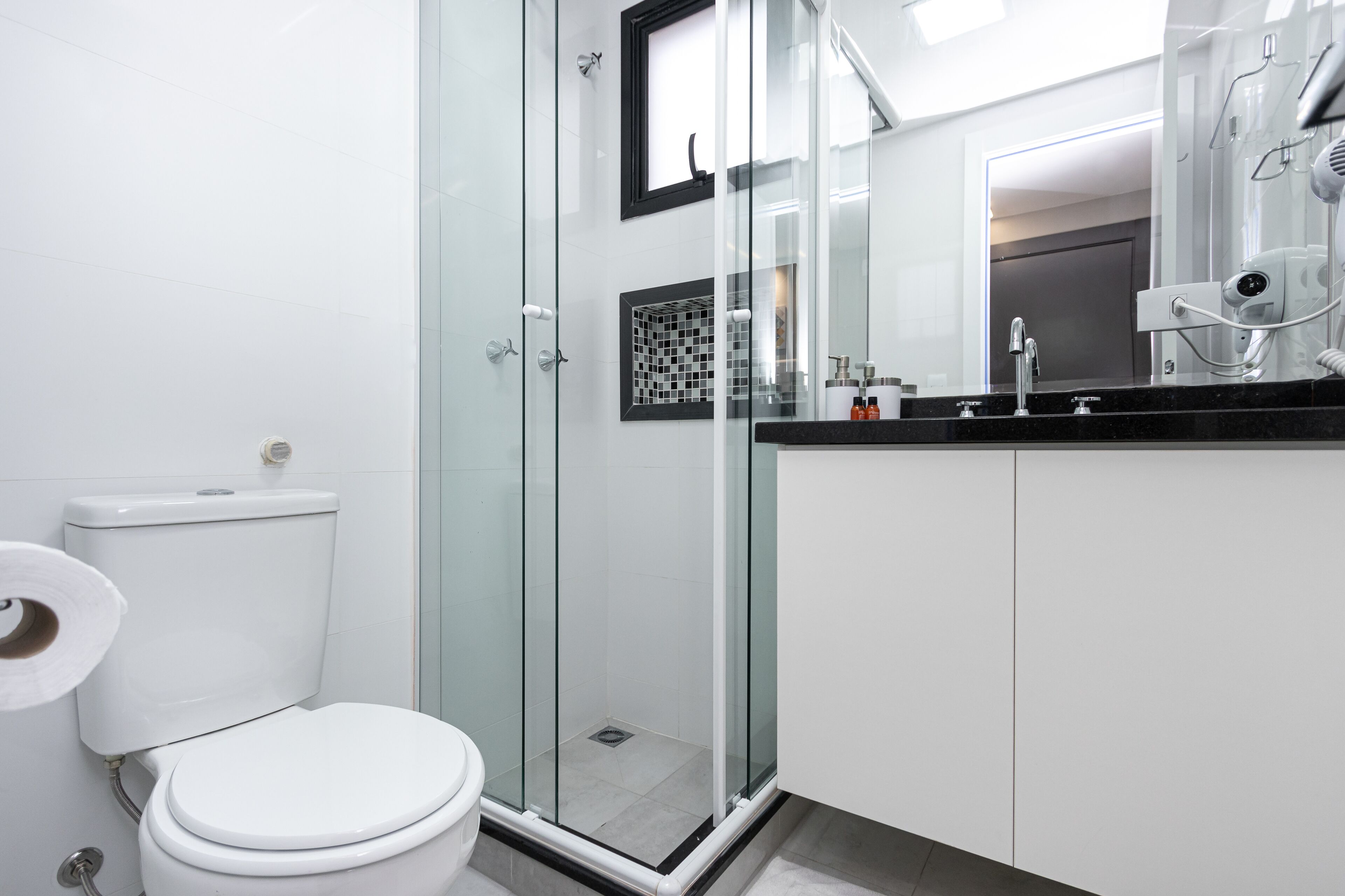 A modern bathroom with a glass-enclosed shower, a toilet, and a vanity with a mirror.