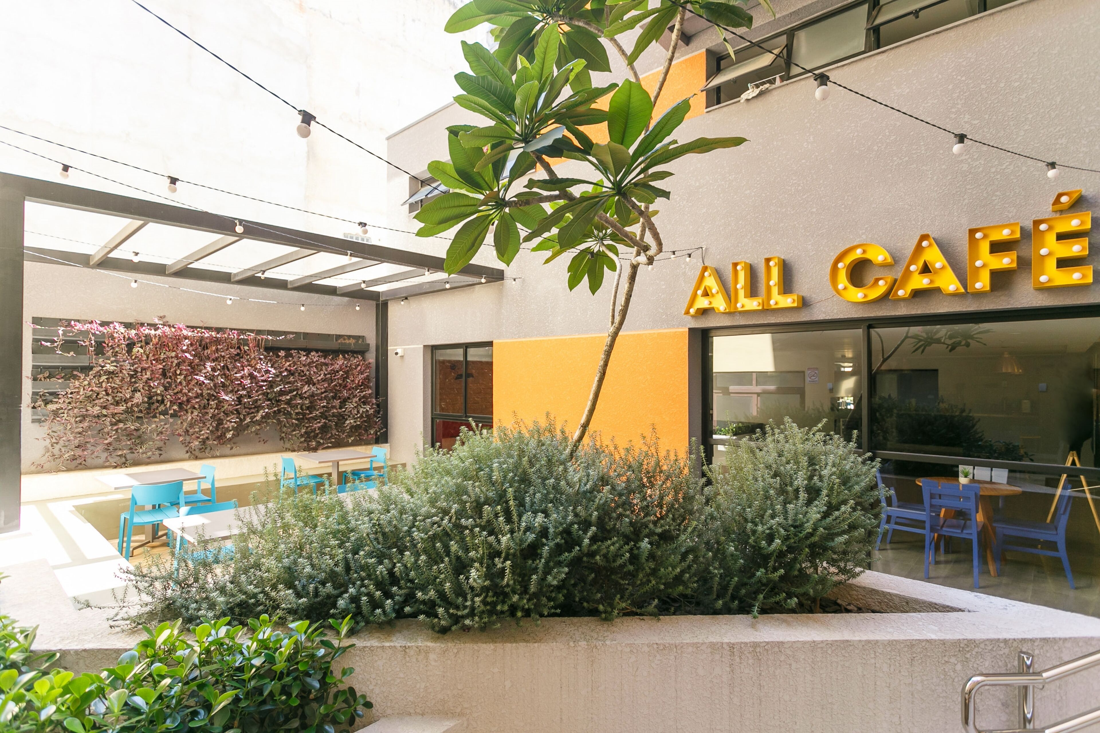An outdoor café area with a seating arrangement and a building with a sign that reads "ALL CAFÉ".