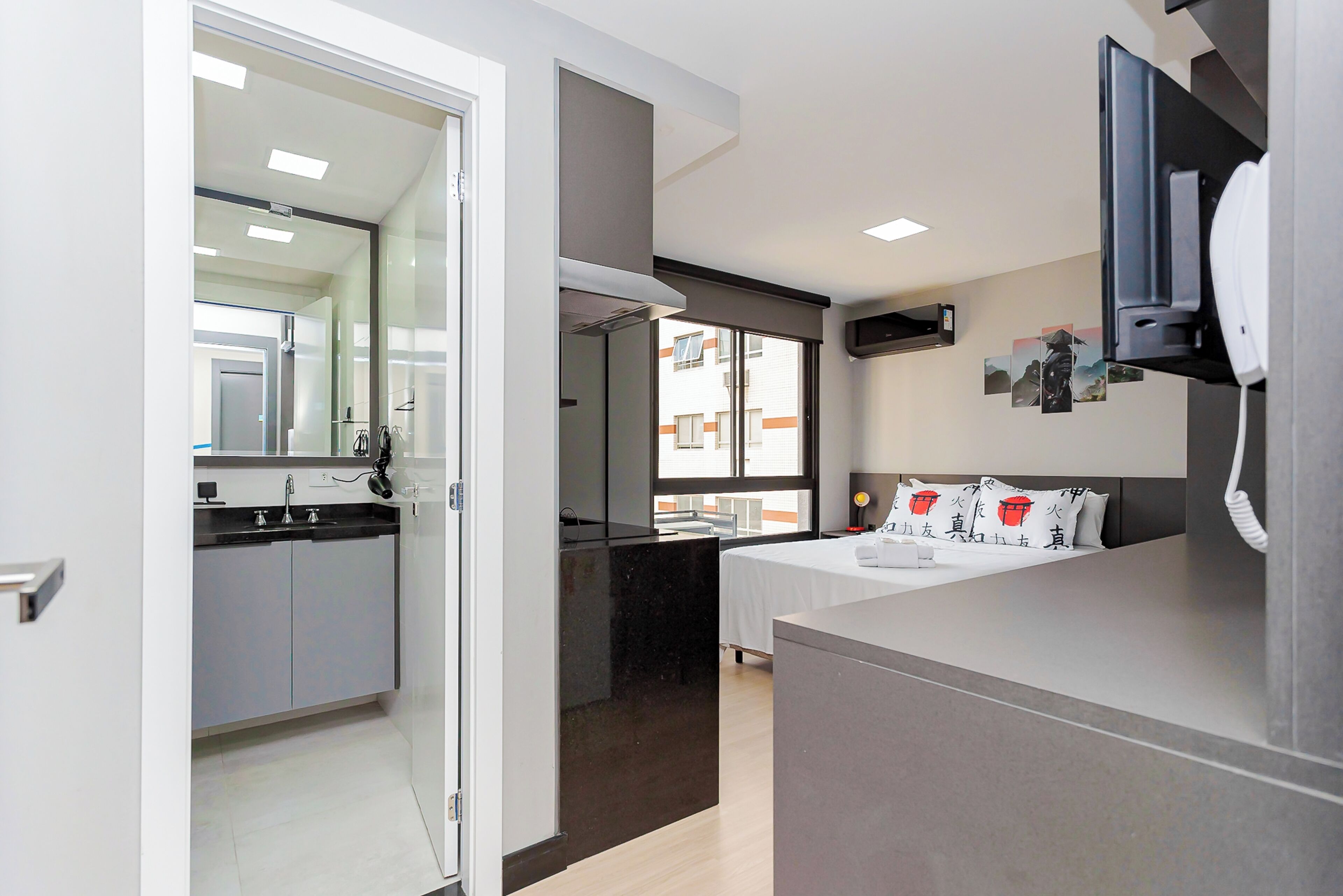 A modern hotel room with a bed, bedside table, and a large window.