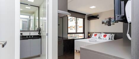 A modern hotel room with a bed, bedside table, and a large window.