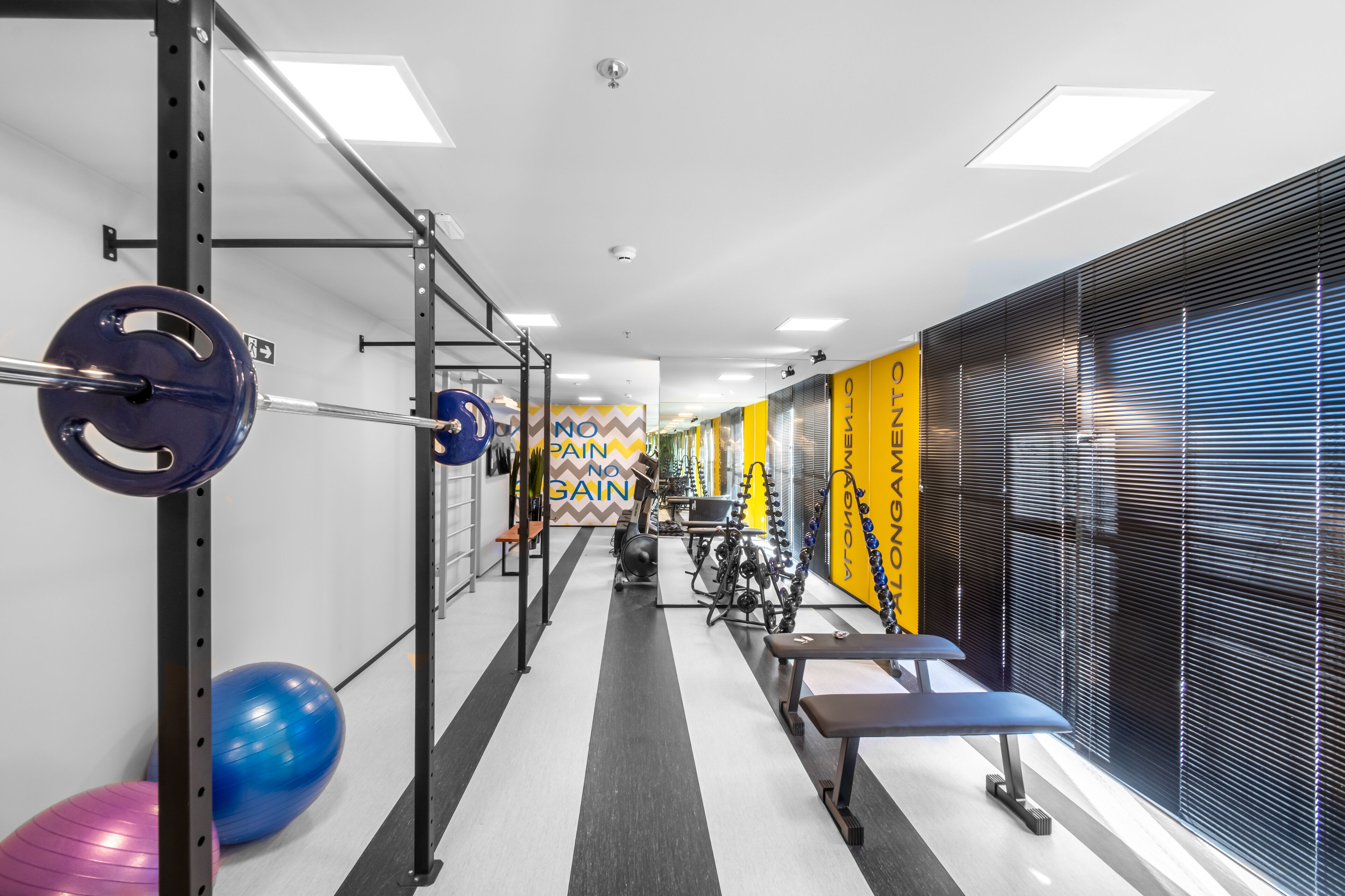 Ett gym med utrustning för styrketräning, träningsbollar och bänkar.