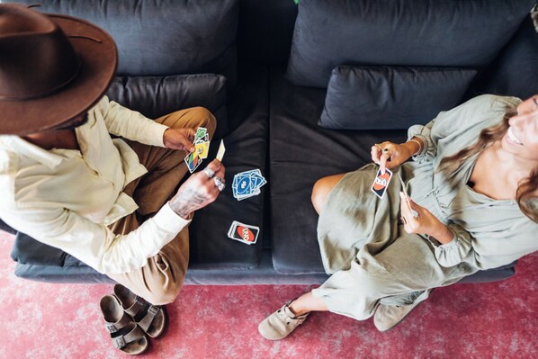 Two people sitting on a black couch with a red floor, playing cards. - Stay Hotel Porto Aeroporto (Maia)