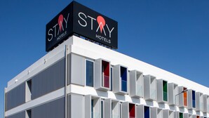 Edificio de Stay Hotels con diseño moderno, que destaca un letrero prominente y una serie de ventanas de colores.