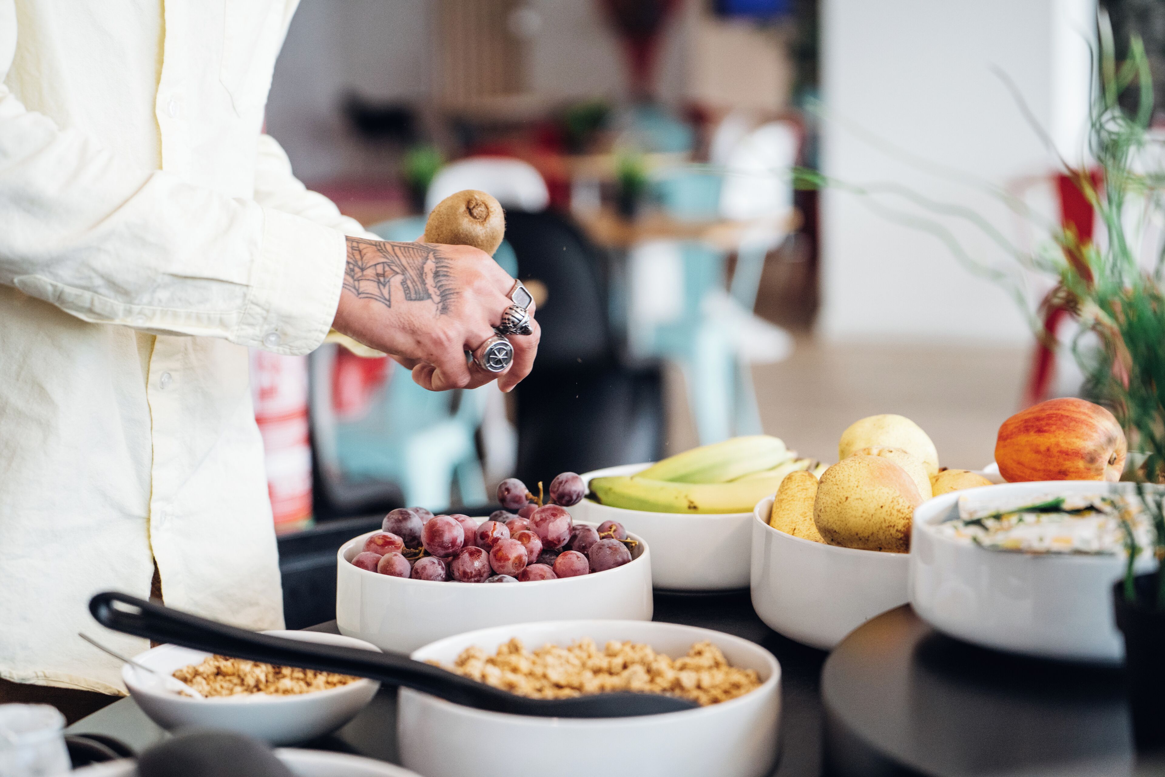 En person laver mad med skåle med frugt og granola.