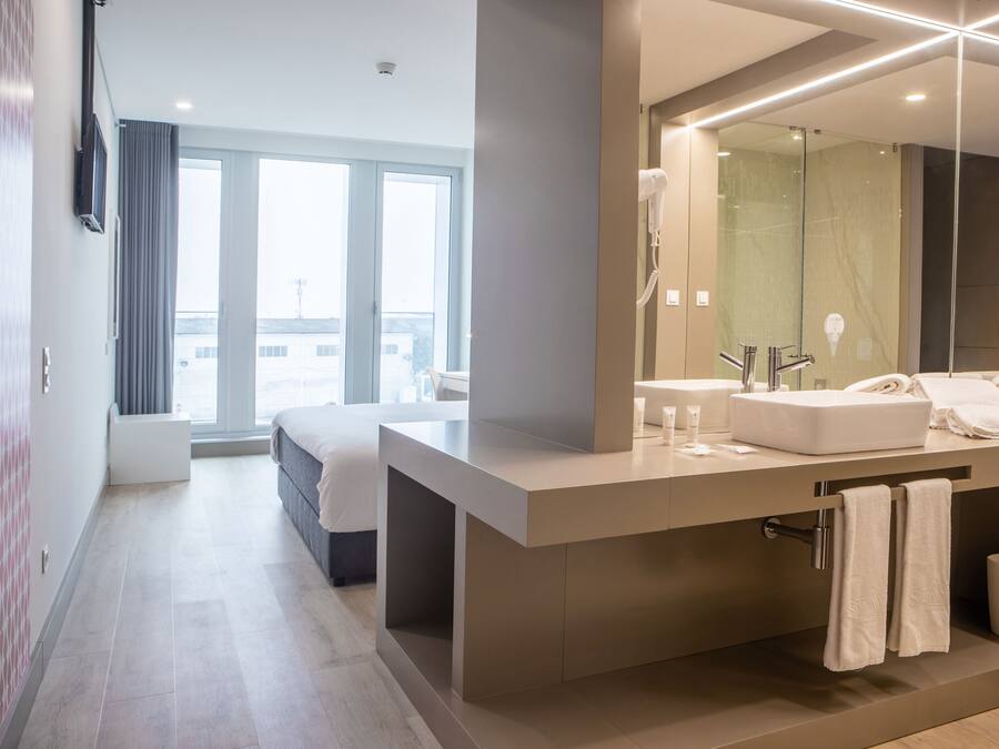 A modern hotel bathroom with a large mirror, a bathtub, and a vanity with a sink and towel rack.