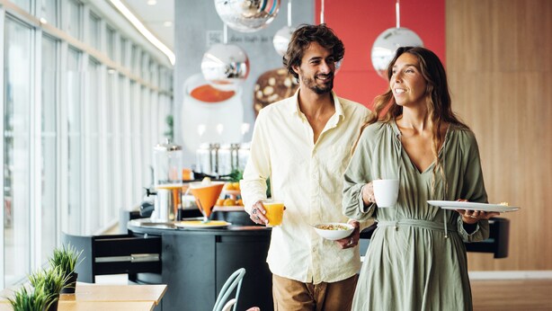 Un espacio de oficina moderno con una larga barra, una máquina de café y una planta en maceta.