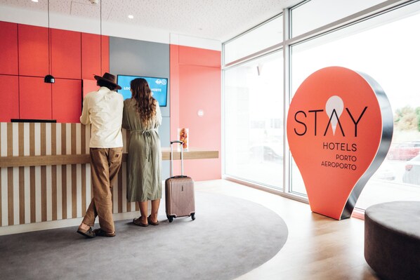 Een receptiegedeelte met een 'STAY' bord, een balie en een groot raam.