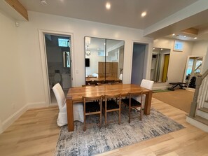 A dining area with a wooden table and chairs, a rug, and a large mirror. - Pool/5 min walk to Beach/Restaurants/Museums- Village House w/backyard (Sag Harbor)