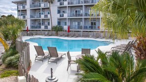 Un hôtel à plusieurs étages doté d’un espace piscine, comprenant des chaises longues et une clôture en bois.
