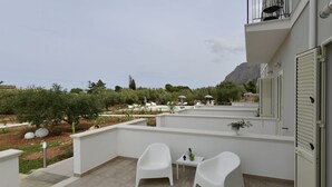 A balcony with two white chairs, a small table, and a potted plant. - Inkantu B&B (Terrasini)