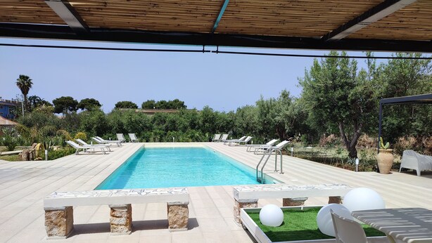 A swimming pool with lounge chairs and a covered seating area. - Inkantu B&B (Terrasini)