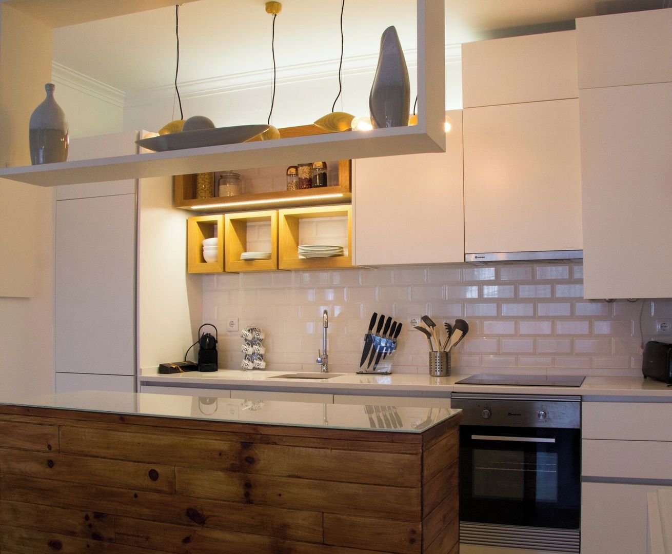 A modern kitchen with a wooden island, white cabinetry, and a built-in oven.