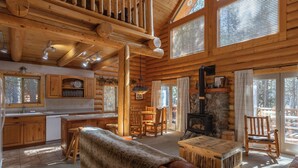 A log cabin interior with a kitchen, dining area, and fireplace.