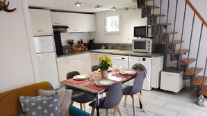 Een moderne keuken met witte kasten, een eettafel gedekt voor vier personen en een trap met houten treden.