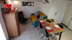 Een compacte woonruimte met een kitchenette, een eethoek en een bank.