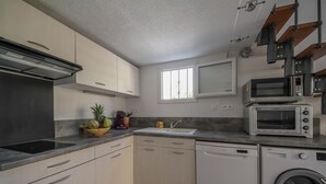 Een praktische keuken met een magnetron, broodrooster, spoelbak en vaatwasser.