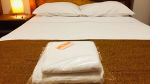 Un lit bien fait, avec du linge de lit blanc, une tête de lit en bois et une table de chevet avec une lampe.