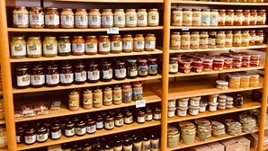 Une étagère de magasin remplie de différents pots de confitures et de cornichons.