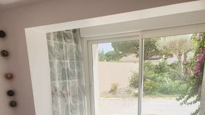 Une chambre à coucher avec un lit, une grande fenêtre et une vue sur un jardin.