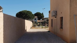 Un étroit sentier de gravier mène à un bâtiment à la façade beige.
