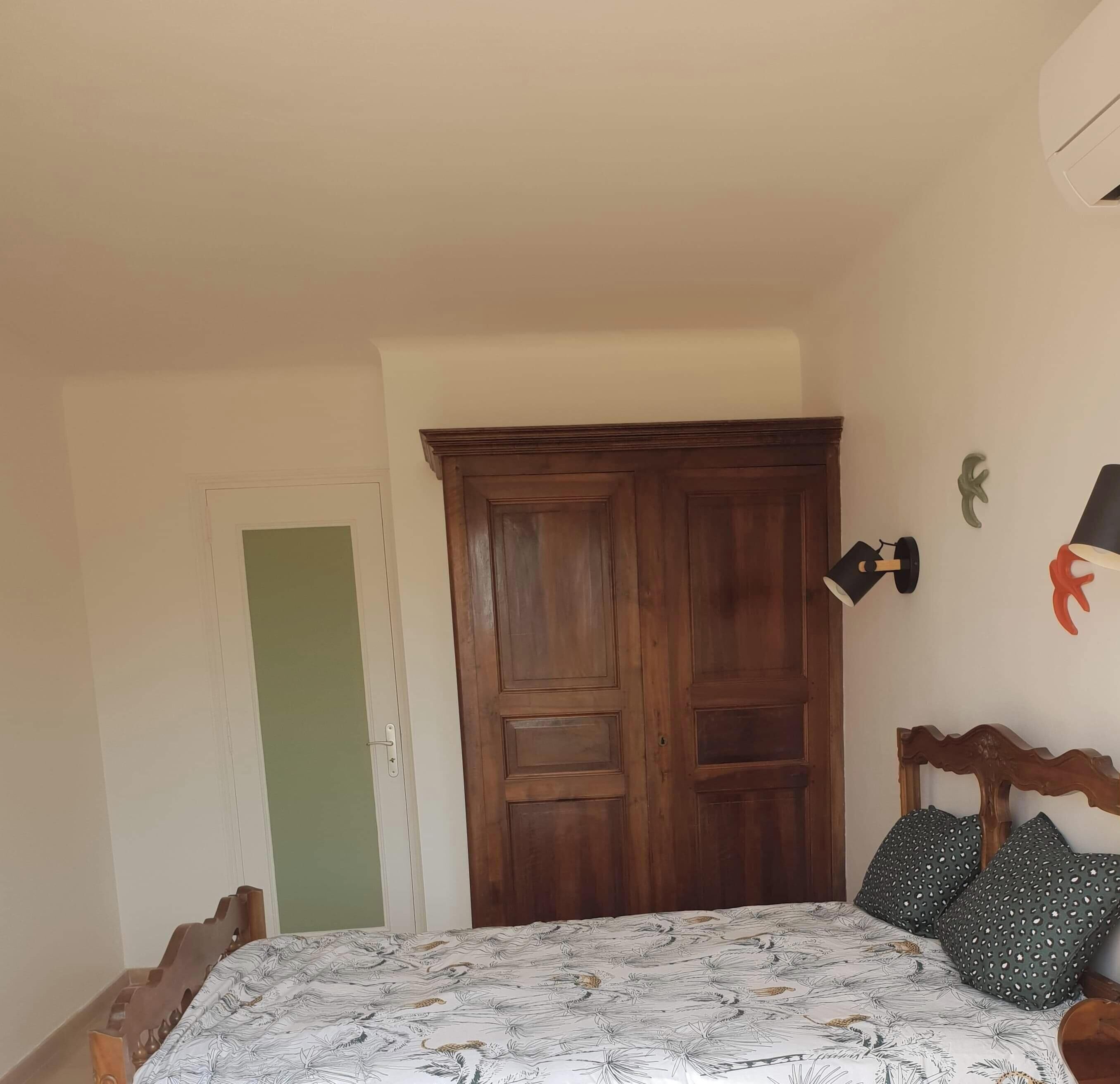 Une chambre à coucher avec un lit, une armoire en bois et une porte.