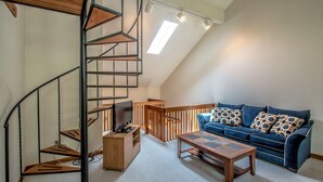 Ein Loft-Zimmer mit Wendeltreppe, einer Sitzecke und einem Holztisch.
