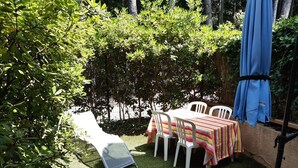 A patio area with a table and chairs, surrounded by greenery and a blue umbrella. - Studio with private garden (Sanary-sur-Mer)