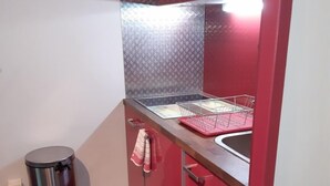 A compact kitchen with a stainless steel sink, a red countertop, and a trash can. - Studio with private garden (Sanary-sur-Mer)