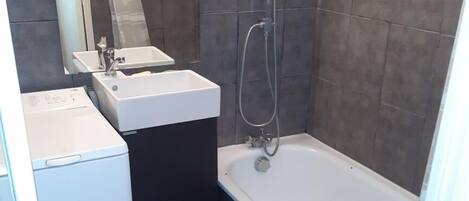 Un baño pequeño con un lavamanos blanco, un espejo y una bañera.