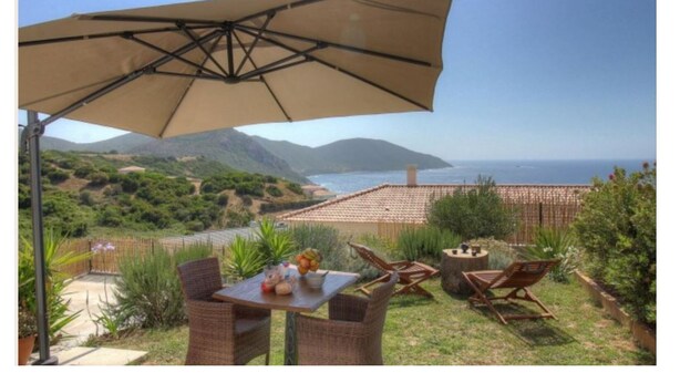 An outdoor patio with a table, chairs, and a large umbrella overlooking a scenic view of the sea and hills. - T2 ground floor villa Magnificent sea view (Villanova)