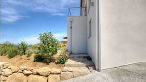 A modern building with a concrete staircase leading to a door, surrounded by a landscaped garden with rocks and plants. - T2 ground floor villa Magnificent sea view (Villanova)