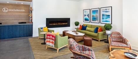 A modern lounge area with a fireplace, sofas, and a reception desk.