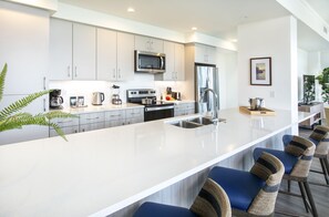 A modern kitchen with white cabinets, stainless steel appliances, and a central island with bar stools.