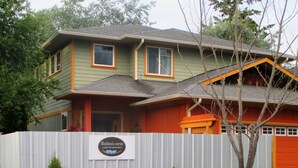 A two-story house with a fenced yard, a sign for 'Robin's Nest', and various plants and flowers.